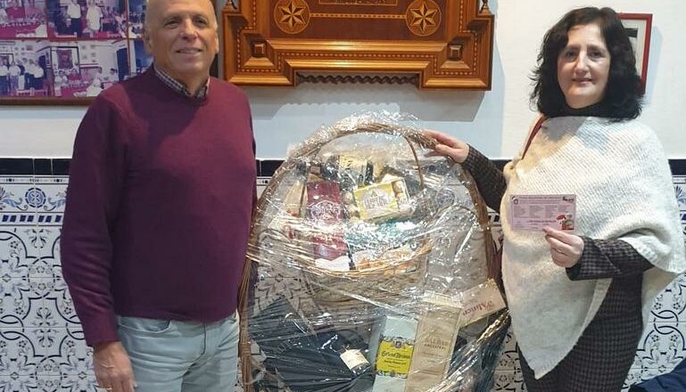 La Peña Sevillista entrega la cesta gourmet de Navidad a la agraciada en el sorteo